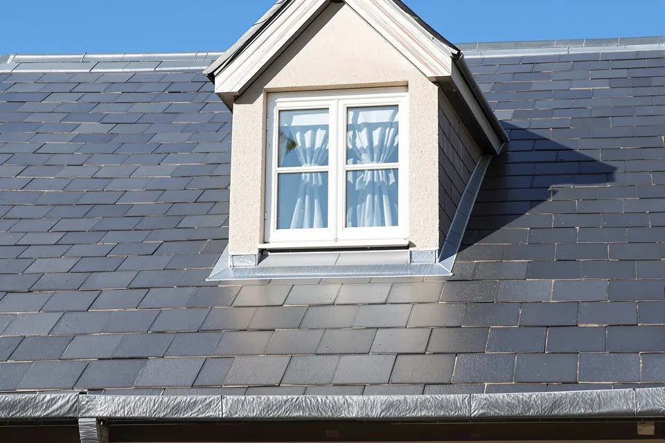 Toiture en ardoises naturelles avec une lucarne et un faîtage en zinc