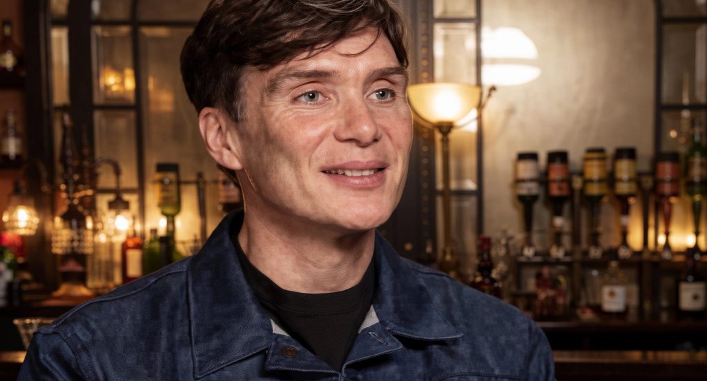 Cillian Murphy apparaît dans une interview, souriant et écoutant le journaliste. Il explique comment Barry Keoghan a décroché son rôle dans Peaky Blinders.